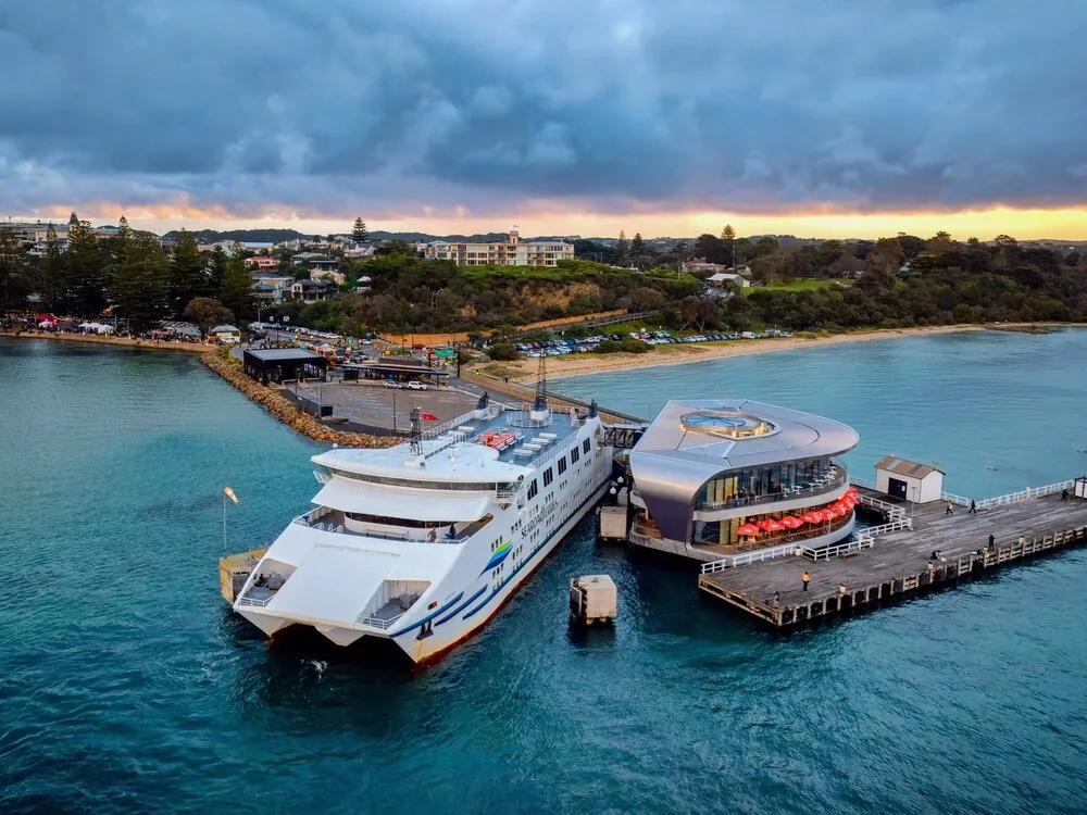A passenger ferry docked at a pier on a bay at dusk